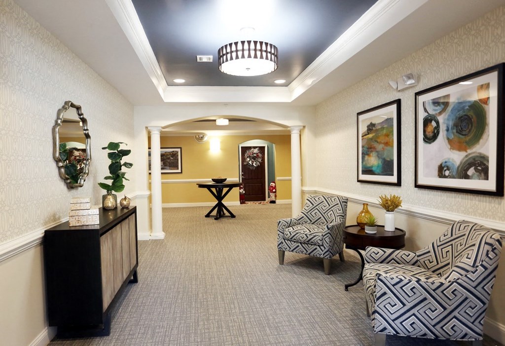 A hallway with a table and chairs and a mirror.