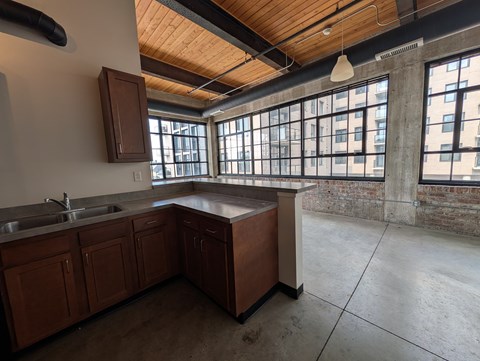 A kitchen with wooden cabinets and a large window.