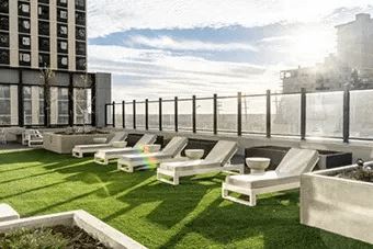 A sunny day at the rooftop with sun loungers and a fence.