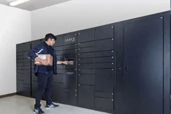 A man in a blue uniform is opening a black safe.