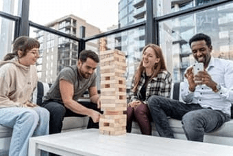Four people playing a game of Jenga in an office setting.