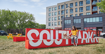 A woman sits on a bench in front of a large red sign that says Southpark.