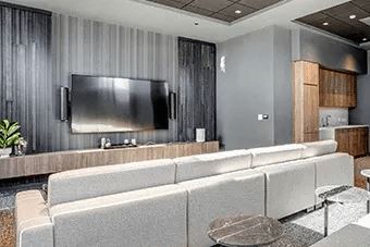 A modern living room with a grey sofa and a flat screen TV mounted on the wall.