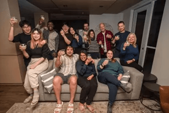 A group of people are sitting on a couch and holding drinks.