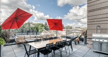A patio with a table, chairs, and red umbrellas.
