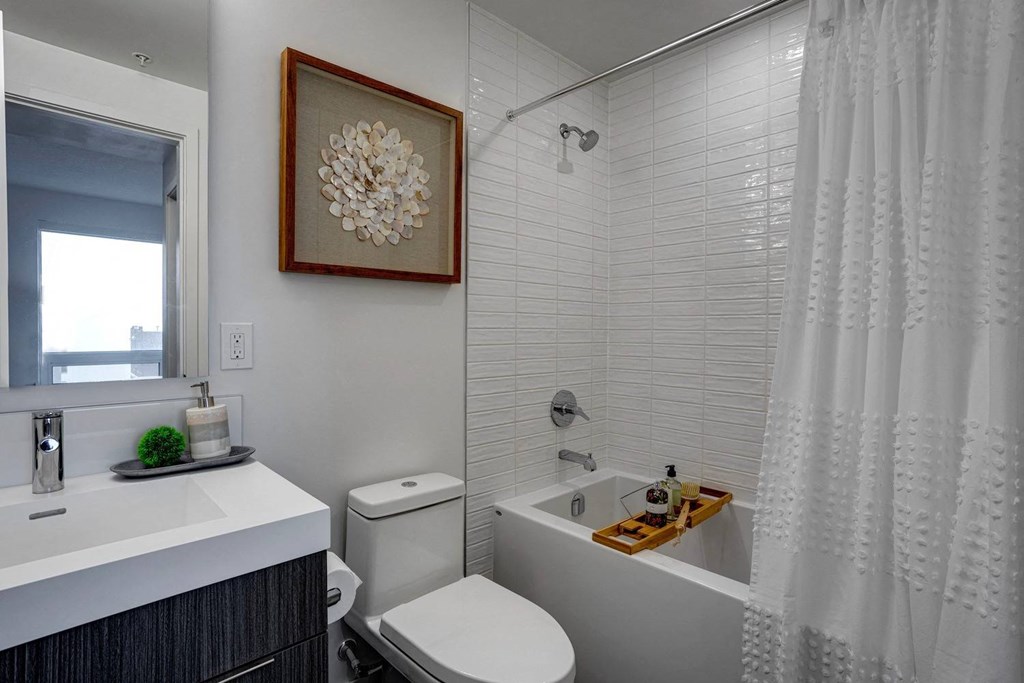 A white bathroom with a toilet, sink, and shower.