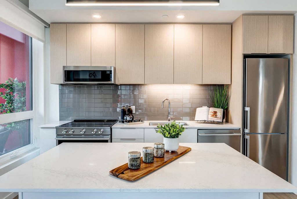 A modern kitchen with a marble countertop and stainless steel appliances.