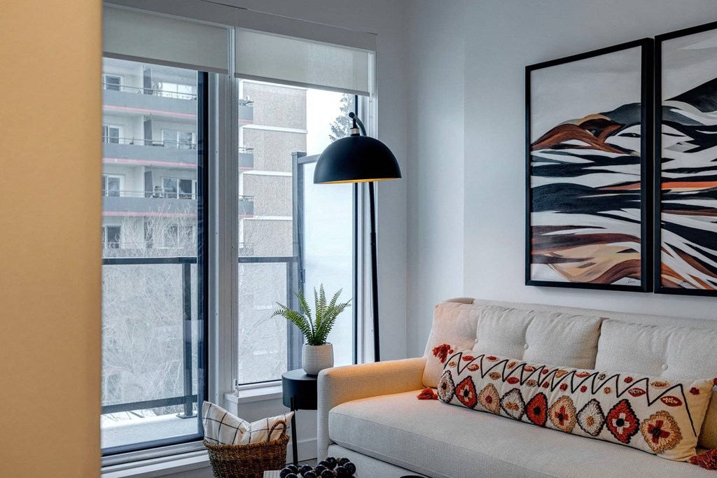 A living room with a white couch and a large abstract painting on the wall.