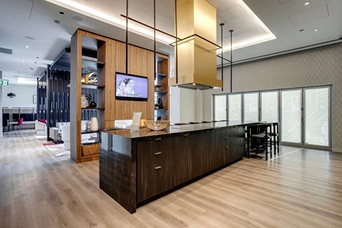 A modern kitchen with wooden cabinets and a television mounted on the wall.