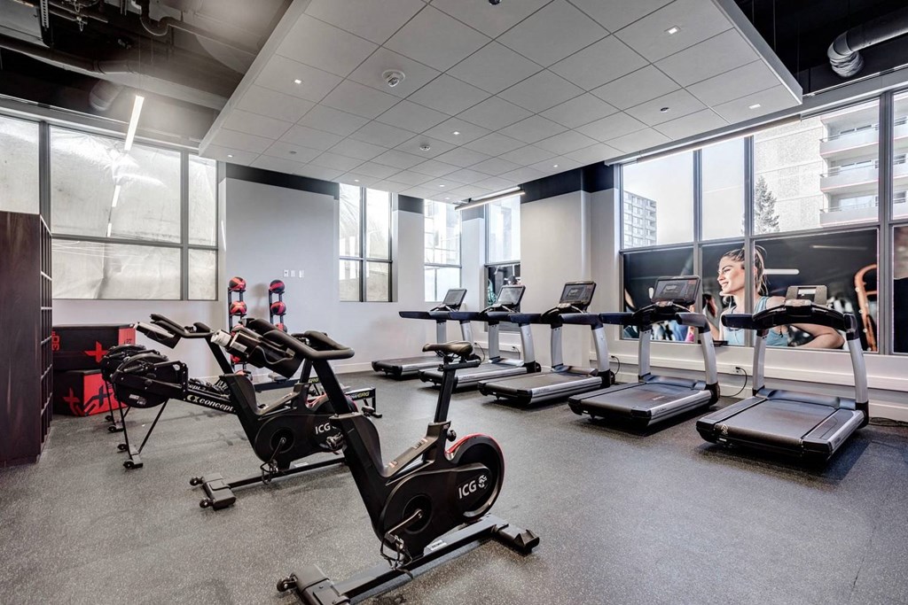 A gym with a woman working out on a rowing machine.