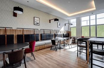 A room with tables and chairs and a long bench.