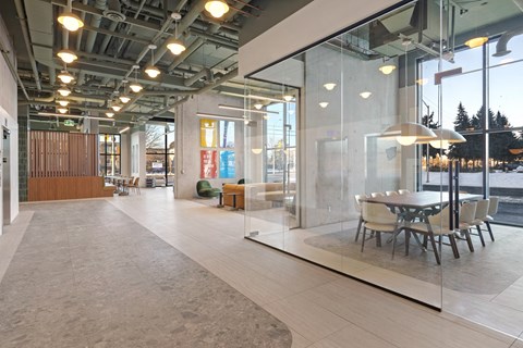 A modern office space with glass walls and a long table with chairs.