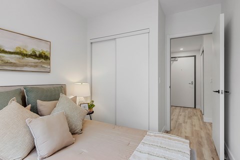 A bedroom with a bed, pillows, a lamp, and a painting on the wall.
