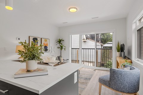 A white kitchen with a grey chair and a potted plant on the counter.