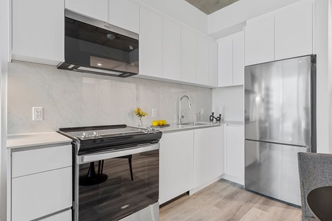 A modern kitchen with white cabinets and a stainless steel refrigerator.