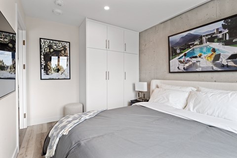 A bedroom with a large bed and a painting of a pool scene on the wall.