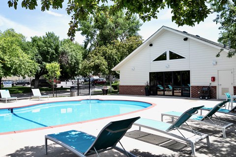 A pool with lounge chairs and a white building in the background. at The Pointe, LaVista, Nebraska