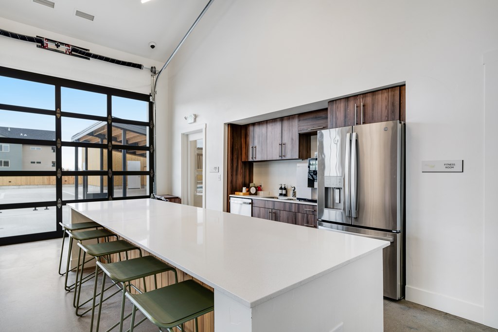 A modern kitchen with a long white counter and a refrigerator.