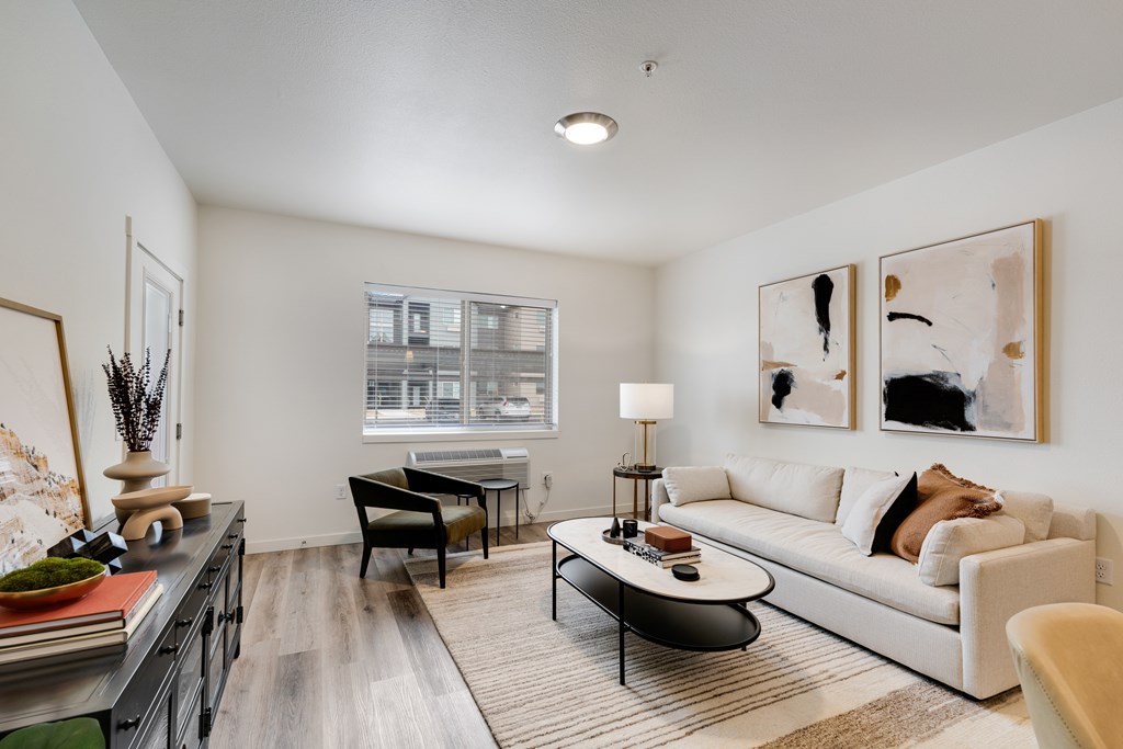 A modern living room with a white sofa, a black coffee table, and two framed artworks on the wall.