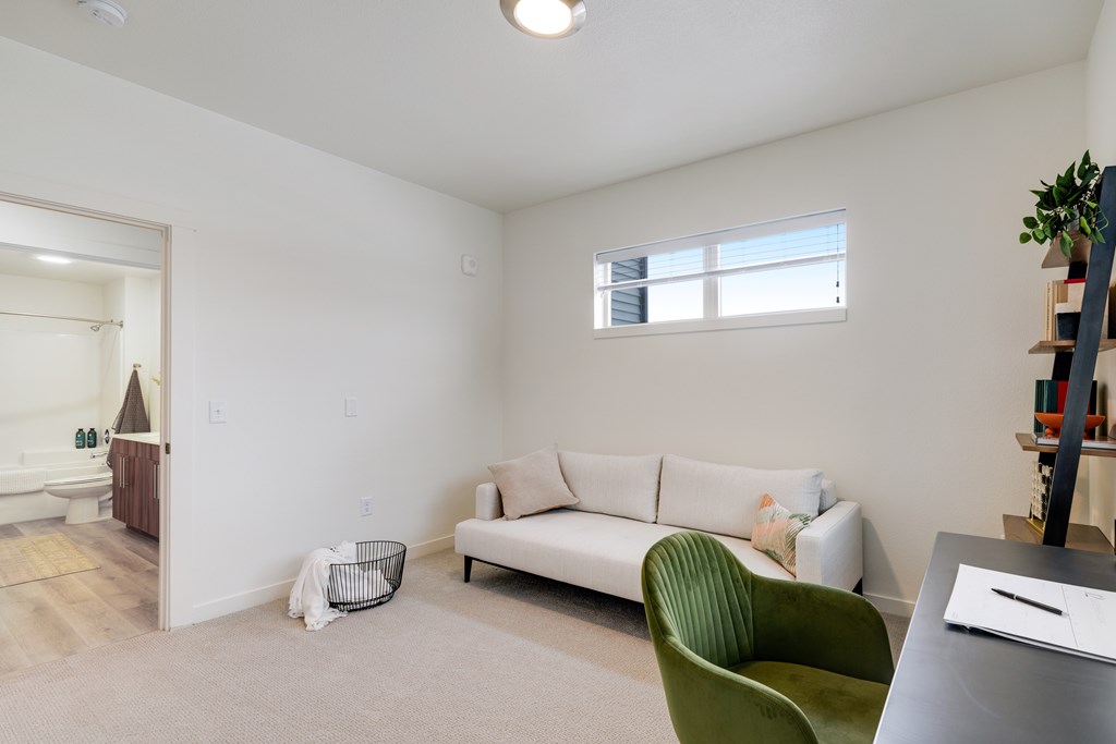 A living room with a white couch, green chair, and a small table.