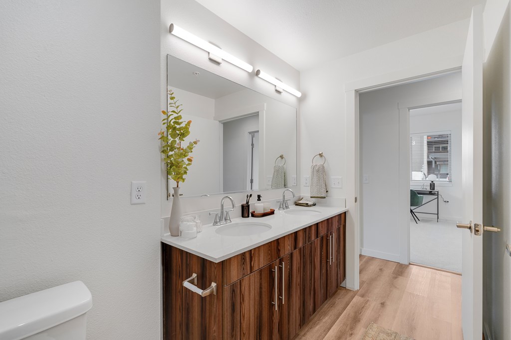 A bathroom with a white tub and a white sink with brown cabinets.