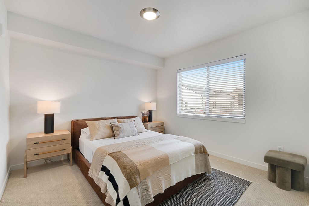 A bedroom with a bed, nightstand, and window.