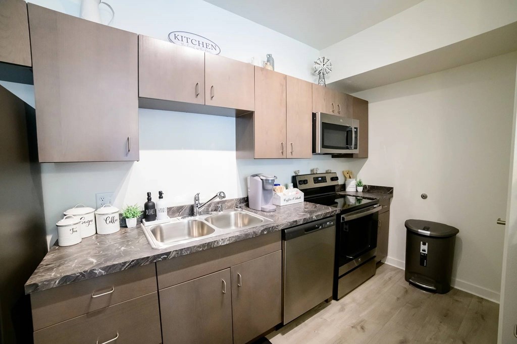 A kitchen with a sink, stove, and microwave.