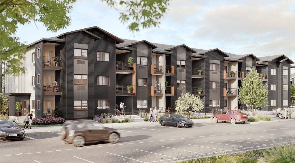 A row of modern apartment buildings with cars parked in front.