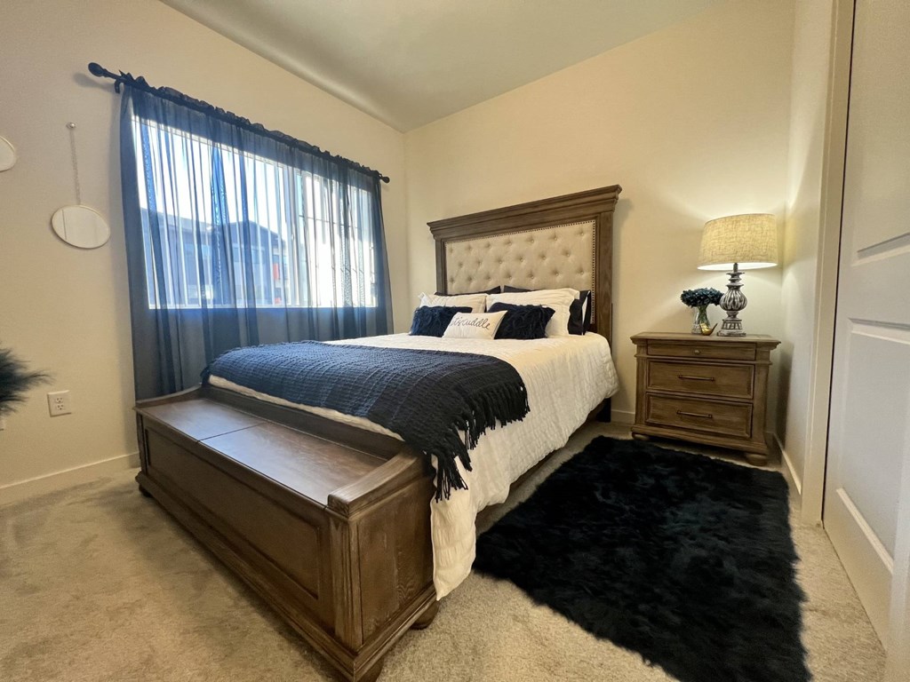 A bedroom with a bed, nightstand, and window.