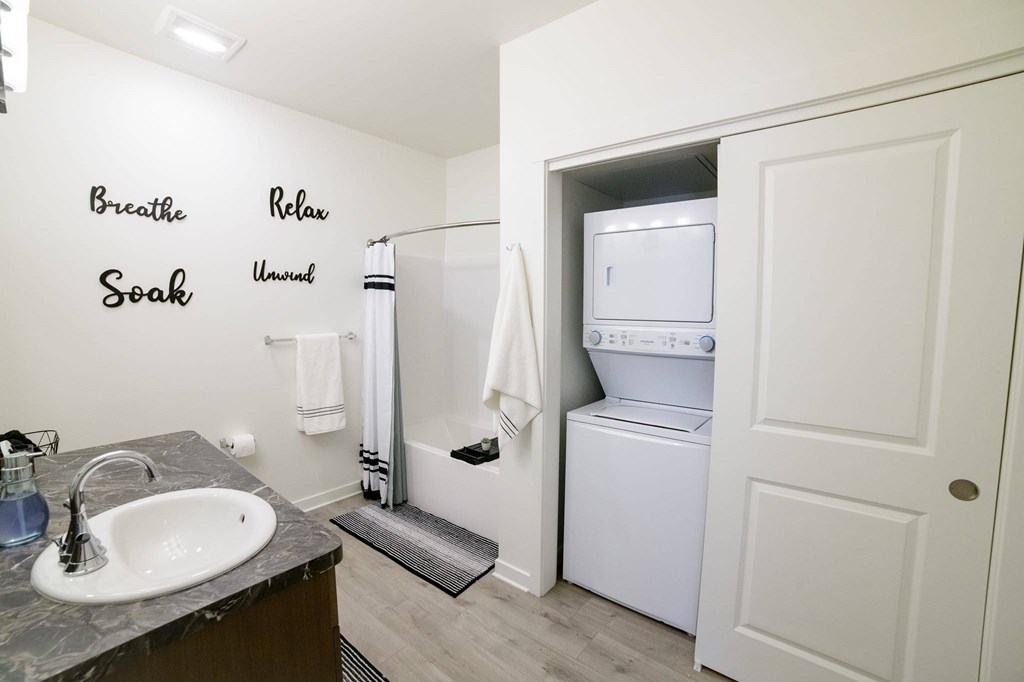 A bathroom with a washer and dryer in the laundry room.