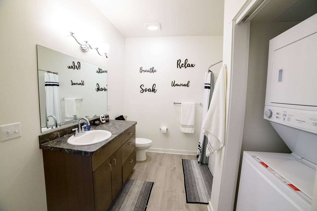 A bathroom with a white fridge and a mirror with the word Relax on it.