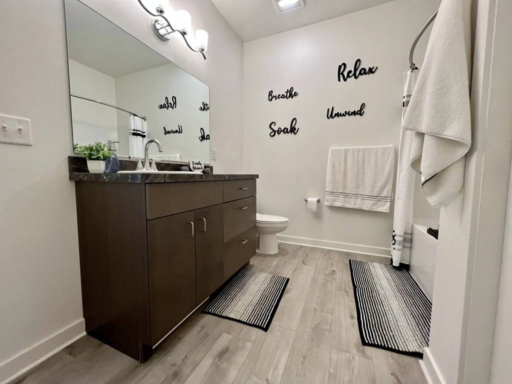 A bathroom with a brown vanity and a mirror with the word Relax on it.
