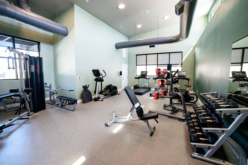 A gym with a variety of equipment including treadmills, weights, and exercise machines.
