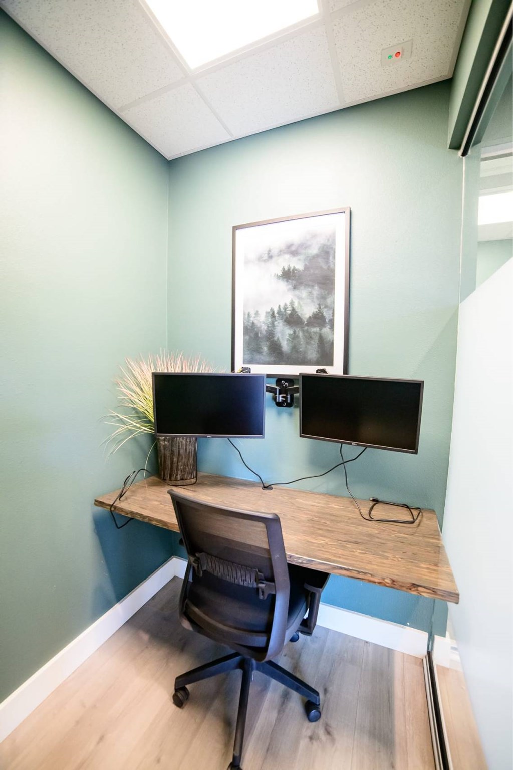 A small office with a desk, chair, and two monitors.