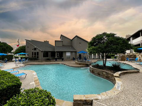A large swimming pool with a stone border and a small waterfall.