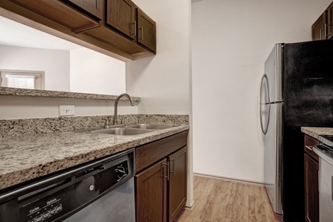 A kitchen with a black fridge and a granite counter top.
