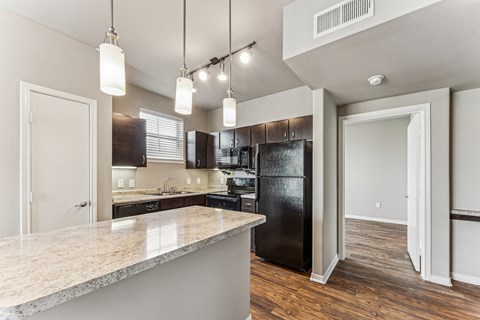 A kitchen with a black refrigerator and a marble countertop.