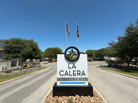 A sign for La Calera Apartments stands in front of a road.