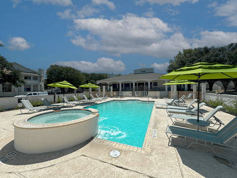 A pool area with sun loungers and umbrellas.