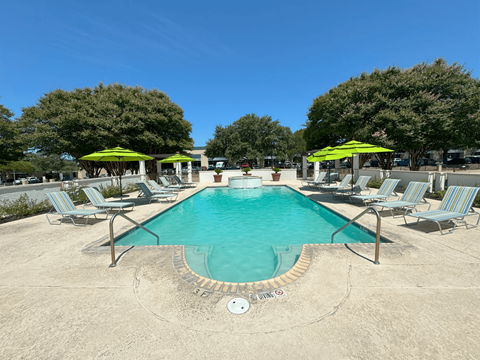 A large swimming pool surrounded by lounge chairs and umbrellas.