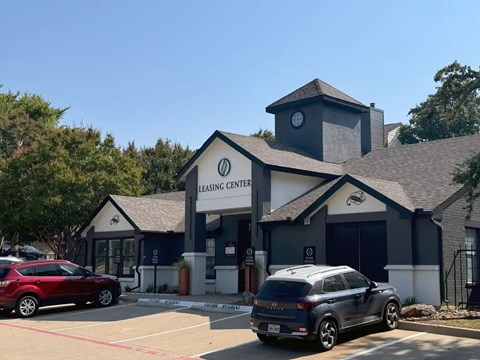 A leasing center with a red car parked in front.