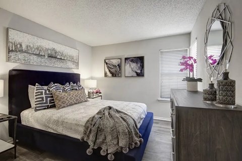 A bedroom with a bed, nightstand, and a mirror.