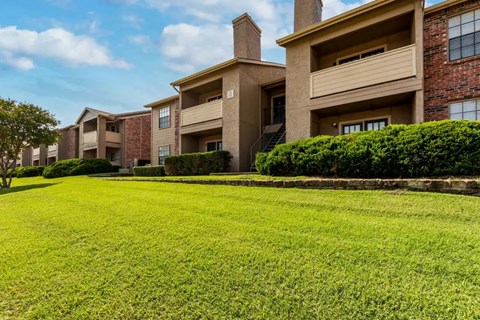 A row of apartment buildings with green lawns in front.