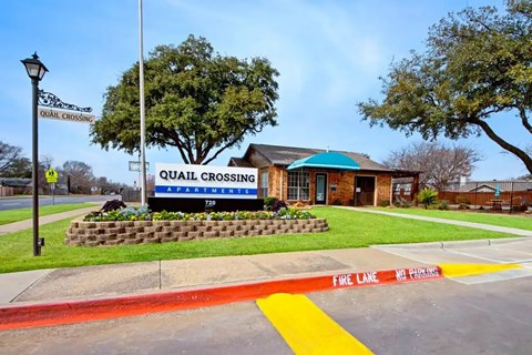 Property entrance sign with landscaping and fire lane at Quail Crossing Apartments, Grand Prairie, Texas