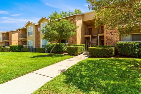 Exterior building view with landscaped lawn at Quail Crossing Apartments, Grand Prairie