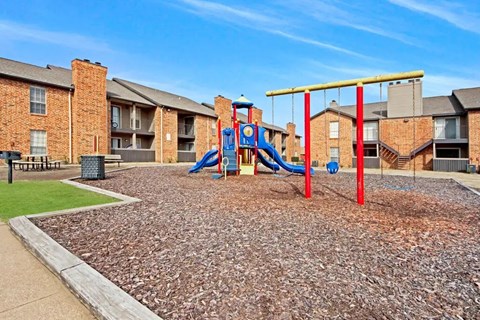 A playground with a red swing set and a blue slide.