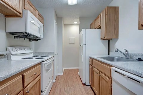 A kitchen with white appliances and wooden cabinets.