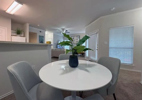 Dining area with white table and upholstered chairs at Indian Creek Apartments, Texas
