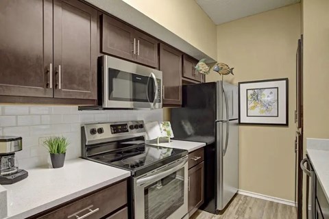 A kitchen with brown cabinets and a black refrigerator.