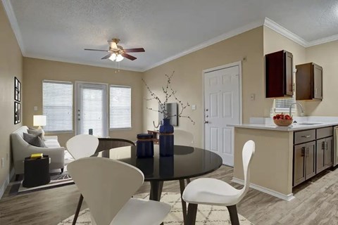 Dining area with modern table and open kitchen at Arbors at Wolf Pen Creek Apartments, College Station, 77840